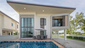 Une maison moderne dotée d’une piscine, de grandes fenêtres et d’un patio couvert.