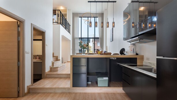 Une cuisine moderne dotée d’un îlot central, d’appareils électroménagers en acier inoxydable et d’un escalier menant à un niveau supérieur.
