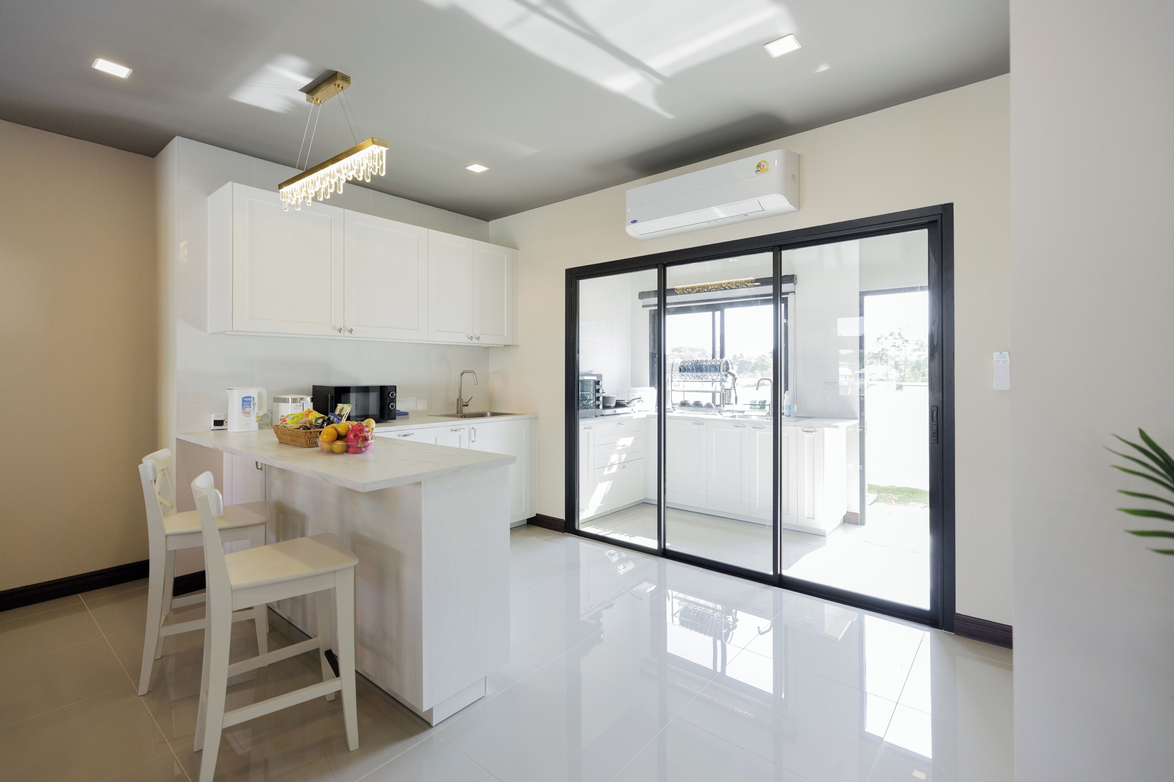 A modern kitchen with white cabinets, a central island, and a glass door leading to a balcony.