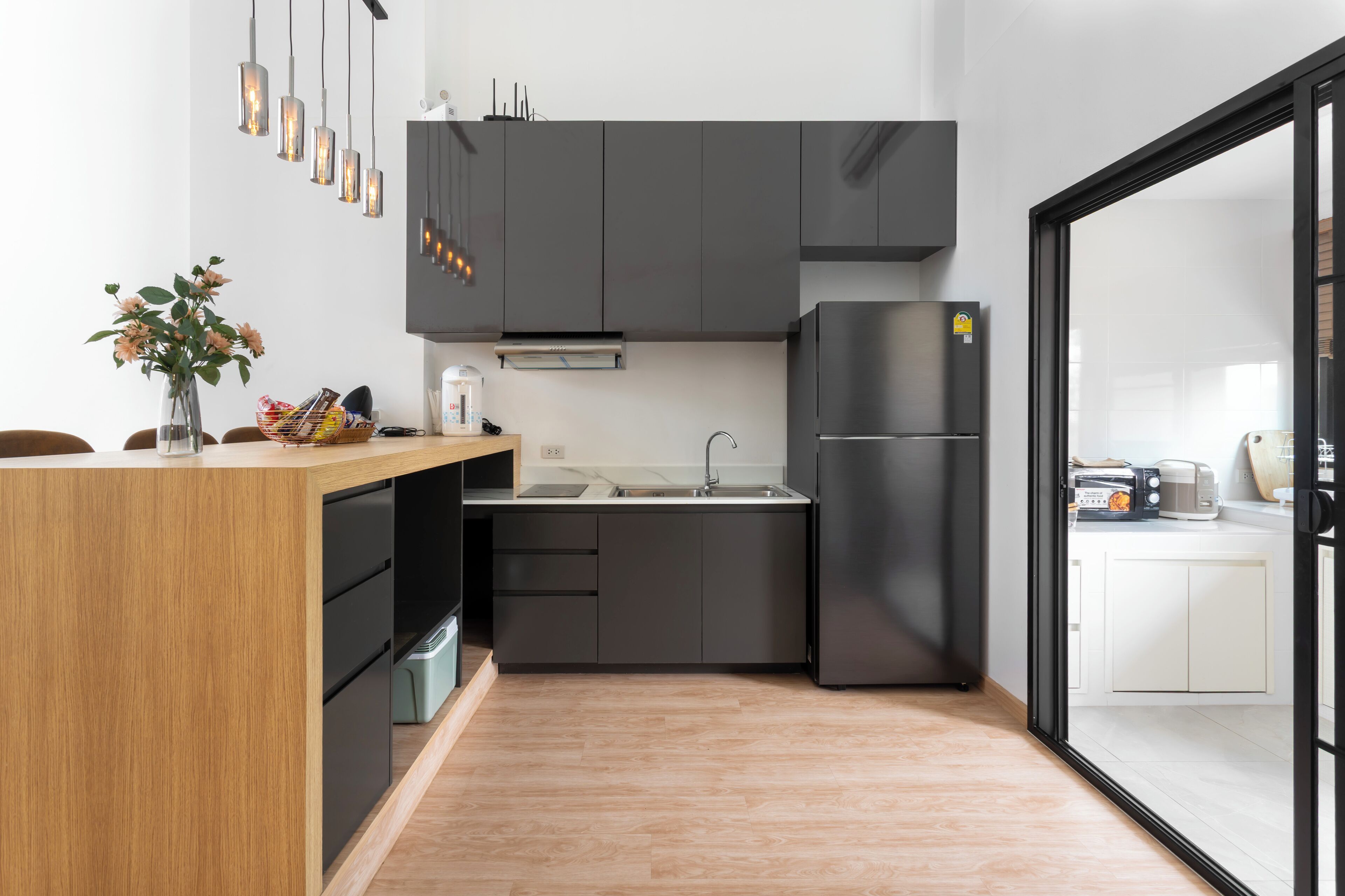 Una cocina moderna con una isla de madera, armarios oscuros y un refrigerador negro.