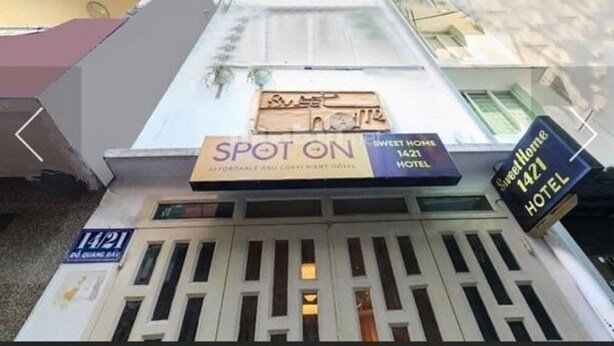 Letrero de hotel con la leyenda "SPOT ON" y "Sweet Home 1421 HOTEL", indicando el nombre y la dirección.