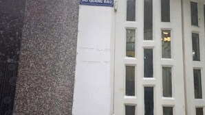 Un edificio con un letrero que dice "14/21 Đô Quang Đầu" y una puerta blanca con varios ventanales.