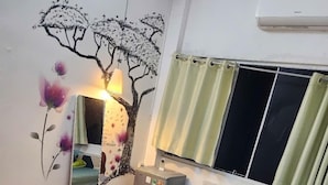Un dormitorio con cama, espejo, cómoda y un mural en la pared.