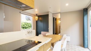A modern kitchen with a built-in stove, white chairs, and a dining table. - Peaceful Apartment With Pool (Turnhout)