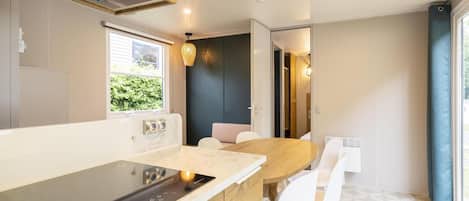 A modern kitchen with a built-in stove, white chairs, and a dining table.