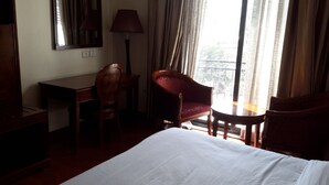 Habitación de hotel con cama, escritorio, silla, una mesita y balcón con vistas.