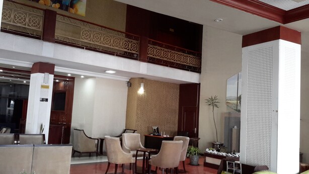 Un vestíbulo amplio con techo alto, una zona de comedor con mesa y sillas, y una pared decorativa con diseños intrincados.