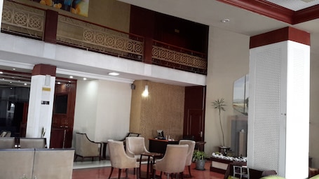 A spacious lobby with a high ceiling, a dining area with a table and chairs, and a decorative wall with intricate patterns.