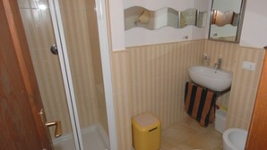 Ein Badezimmer mit Dusche, Waschbecken, Toilette und einem kleinen Mülleimer.