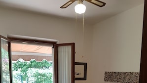 Ein Schlafzimmer mit einem Bett, einem Fenster mit Vorhängen, einem Deckenventilator und einem Wanddekor.