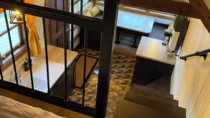 A multi-level wooden interior with a staircase, a dining area, and a kitchen. - Classy Hillside Tiny House (Monarch)