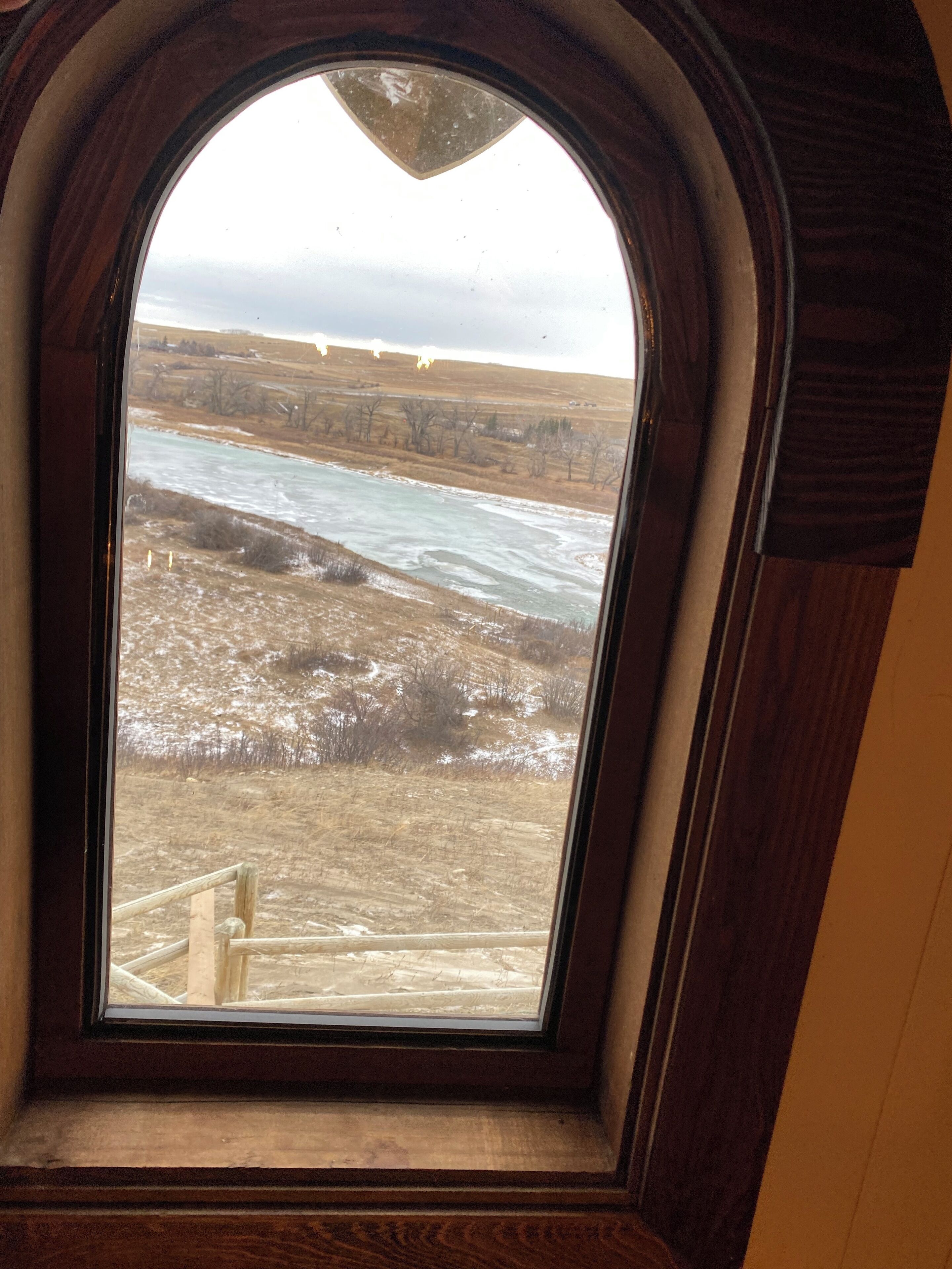 A view through a wooden-framed window of a river and surrounding landscape.