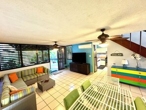 Relax in this spacious living area with a sofa set, dining table, and mounted TV for entertainment.