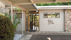 A modern building with a covered entrance, stone walls, and a small garden area.