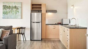 A compact kitchen with a refrigerator, microwave, and wooden cabinets.