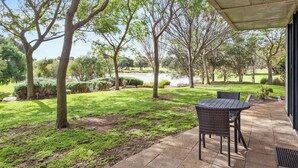 A patio with a table and chairs, surrounded by trees and a lawn. - Petra Olive 5 (Yallingup)