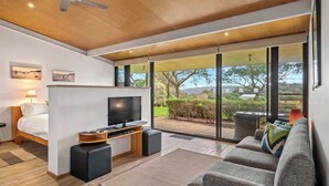 A modern bedroom with a bed, TV, and a sofa. - Petra Olive 3 (Yallingup)