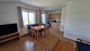 Un espacio habitable compacto con comedor, cocina y televisor.