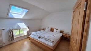 Un dormitorio con tragaluz, estructura de cama de madera y una mesita de noche.
