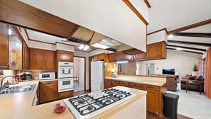 Un'ampia cucina con mobili in legno, un'isola centrale, un piano cottura e un frigorifero.