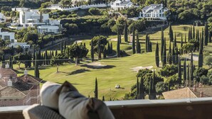 A view from a balcony overlooking a golf course with modern houses in the background.
