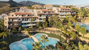 A resort with multiple buildings, a large pool area, and a mountainous backdrop.
