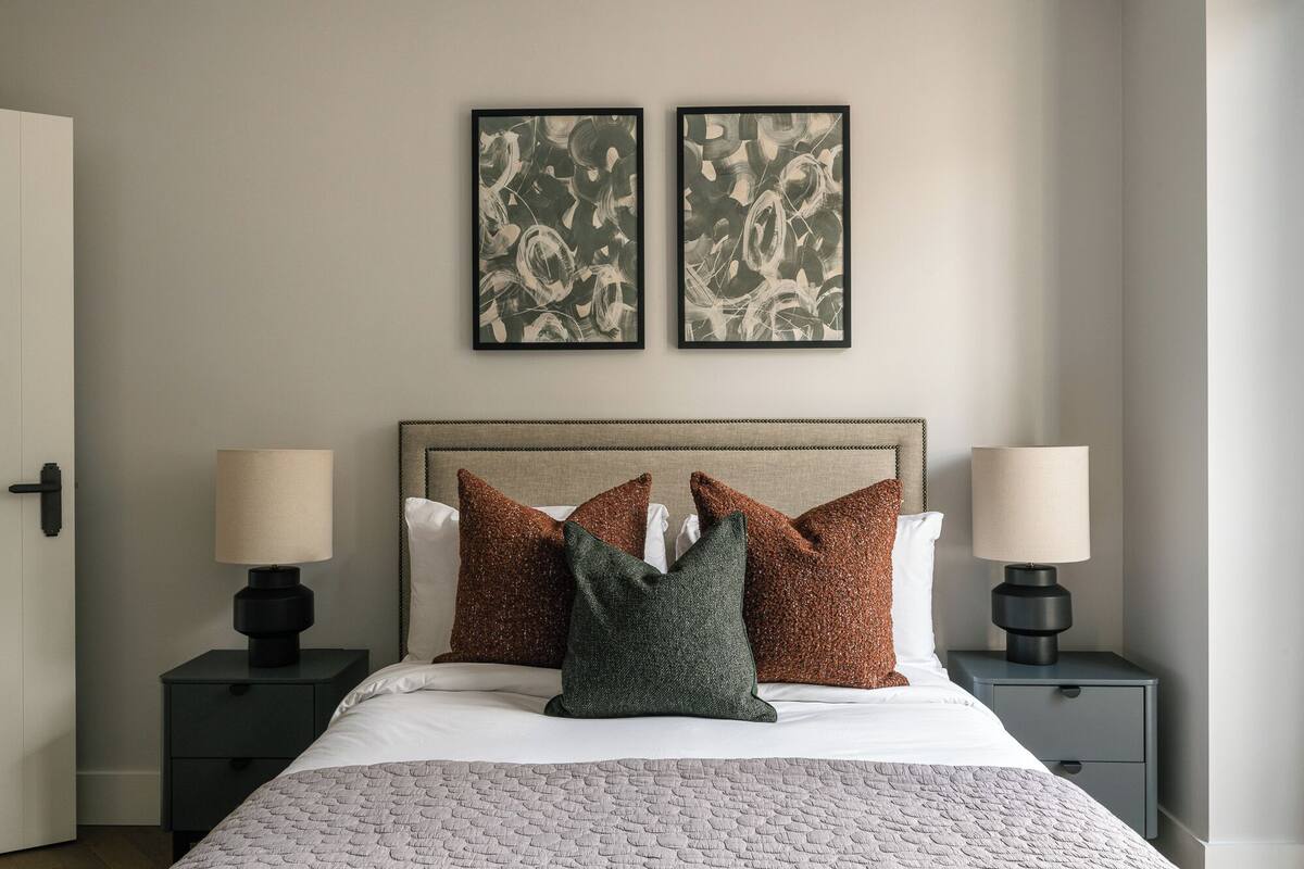 Una cama bien tendida con un edredón texturizado, dos lámparas de noche y un cabecero con un diseño decorativo.