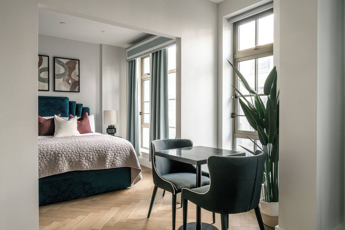 Un dormitorio moderno con cama, escritorio y sillas.