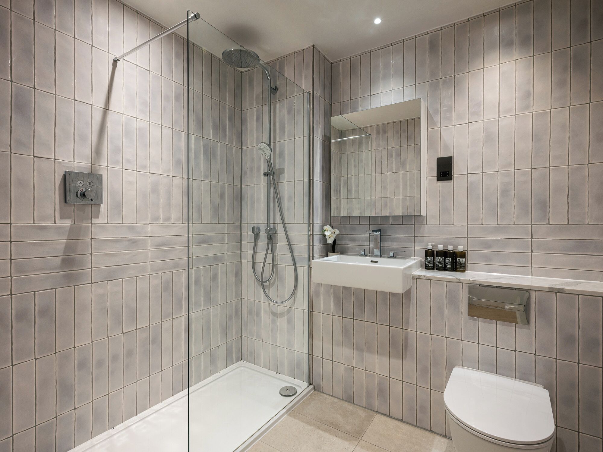 Un bagno moderno con cabina doccia, lavandino e toilette.