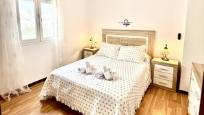 Quarto de hotel com cama, duas mesas de cabeceira com abajures, janela com cortinas e luminária na parede.