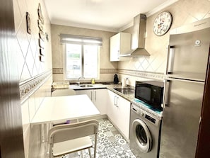 A compact kitchen with a sink, microwave, and stainless steel appliances.