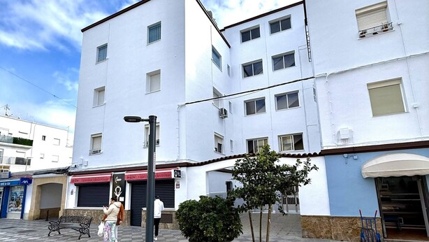 Um edifício com vários andares, fachada plana, diversas janelas e entrada visível.