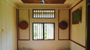 A room with two single beds, a window with bars, and a ceiling fan. - Roemah Abdoe (Harau)