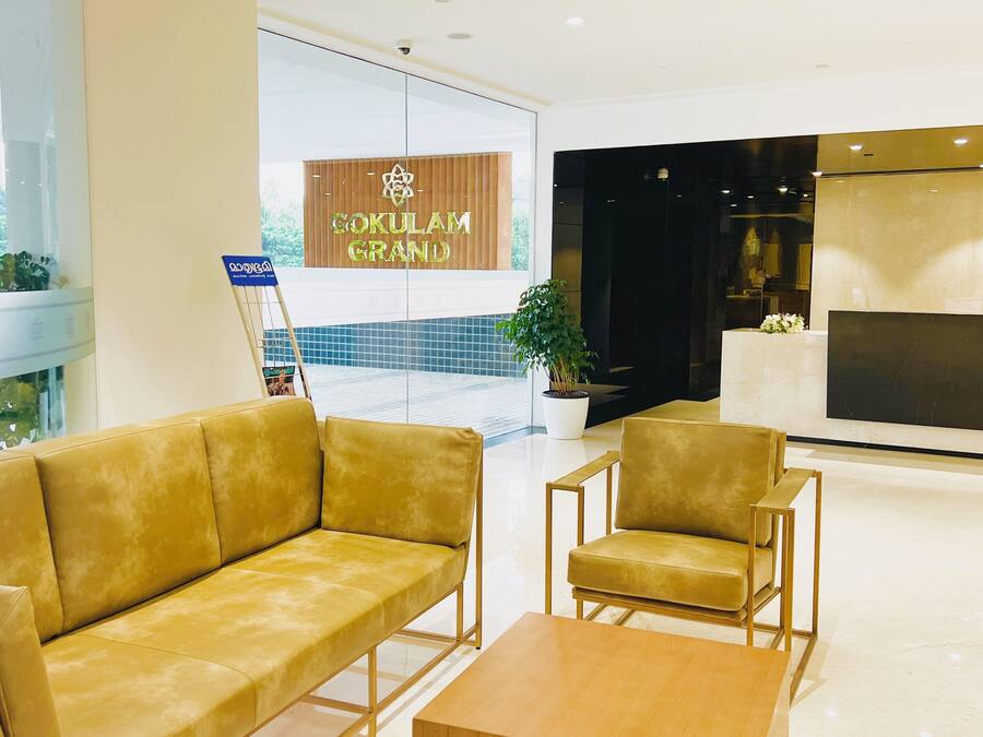 A reception area with a sofa, chairs, and a coffee table. There is a sign that reads "Gokulam Grand".
