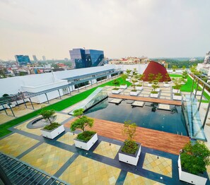 A rooftop pool area with a glass barrier, potted plants, and a view of the cityscape. - Gokulam Grand Kozhikode (Kozhikode)