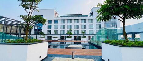 A modern building with a courtyard, featuring a pool, seating areas, and potted plants.