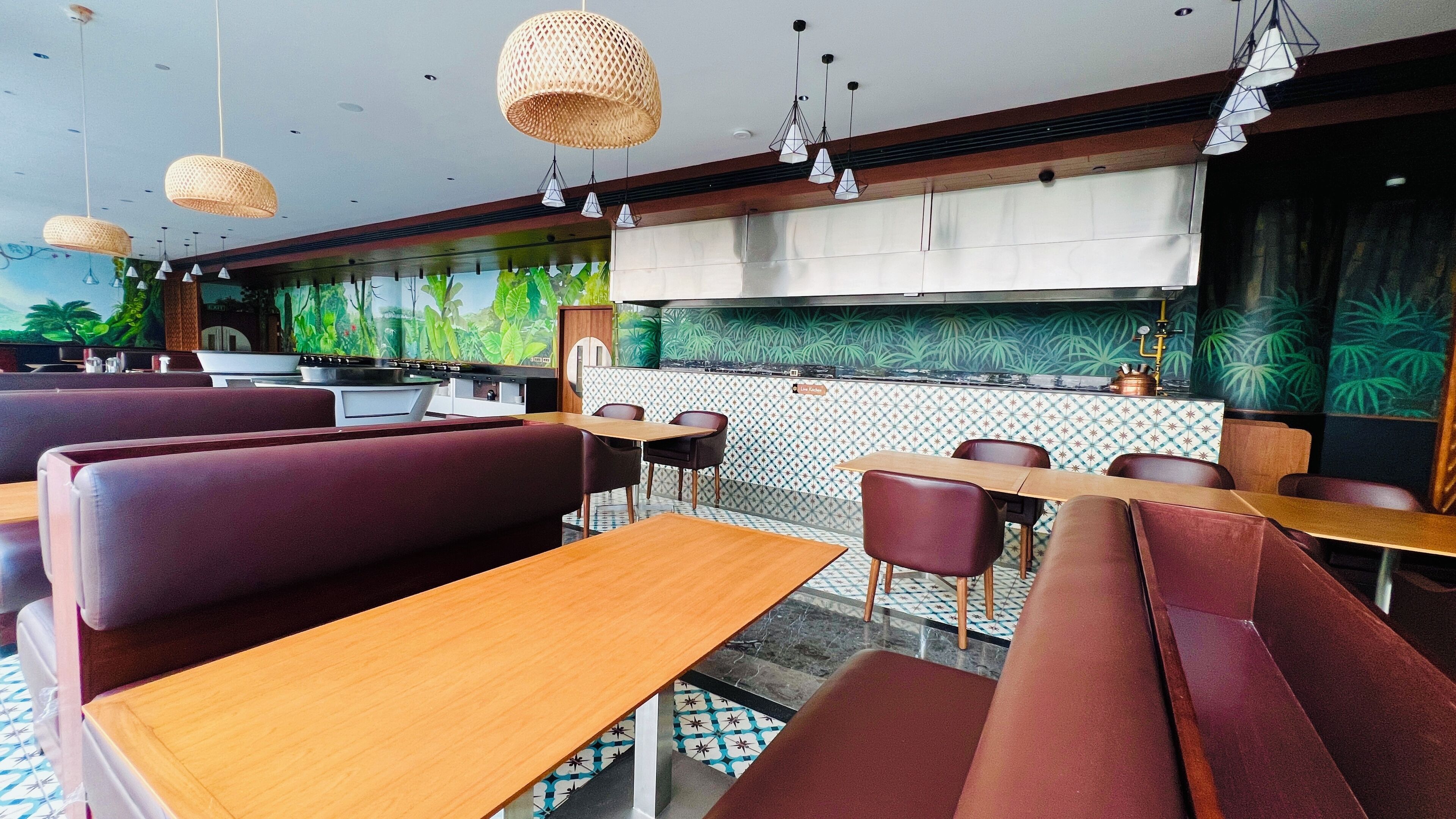 A restaurant with booths and tables, a kitchen area, and hanging lights.