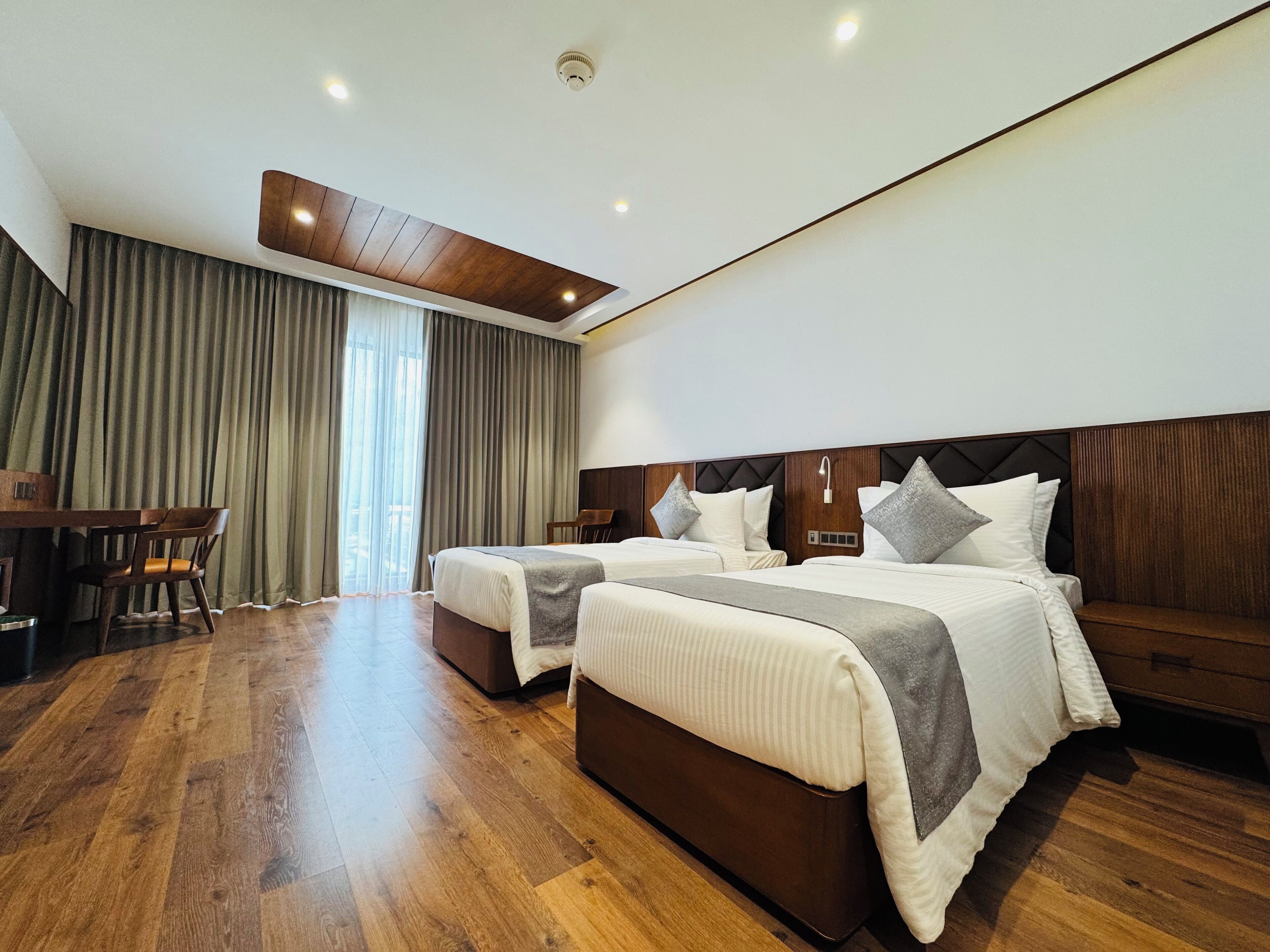 A hotel room with two beds, a desk, and a chair.