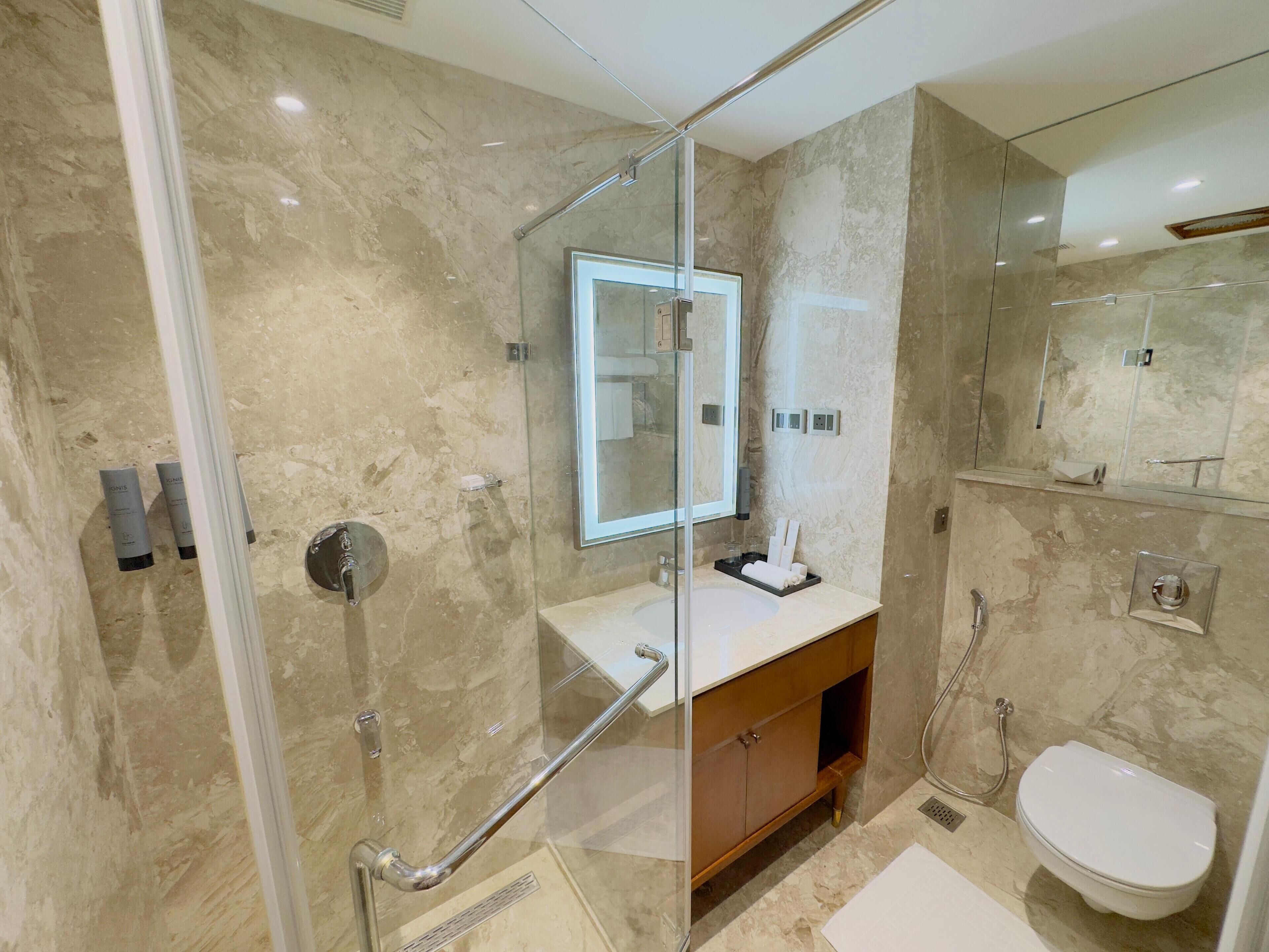 Ein modernes Badezimmer mit einer Duschkabine, einem Waschbecken mit Spiegel darüber und einer Toilette.