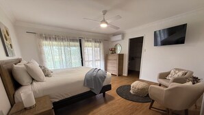 A bedroom with a bed, bedside table, chair, and a TV mounted on the wall. - 3 Bdrm Farm Stay with Goats, Hairy Coos and chickens. Farm Life. You'll Love it! (Postmans Ridge)