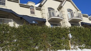 A multi-story building with balconies, a clear blue sky, and dense greenery in front. - Cozy studio in nice Piedmont with AC, WiFi, parking, kitchenette (Piedmont)