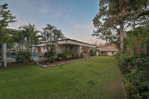 A modern house with a well-maintained lawn, a pool, and a variety of plants.
