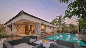 Una casa con fachada de piedra, piscina y mobiliario exterior.