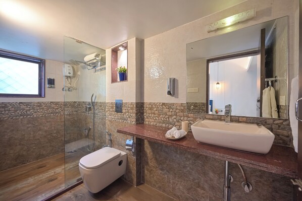 Un baño moderno con ducha envuelta en vidrio, un lavamanos blanco y un espejo grande.