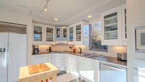 A modern kitchen with white cabinetry, a central island, and built-in appliances. - Striking Design, Fireplaces, Roof Deck (Santa Fe)