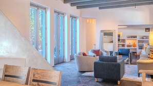A modern living room with a stone floor, large windows, and a variety of seating options. - Striking Design, Fireplaces, Roof Deck (Santa Fe)