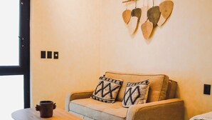 Una sala moderna con un sofá, una mesa redonda de madera y una cama.