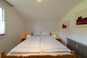 Una habitación con cama doble, lámparas de noche, un radiador y una obra de arte en la pared.