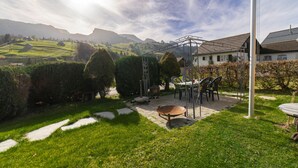 A garden with a pergola, outdoor seating, and a view of the countryside.