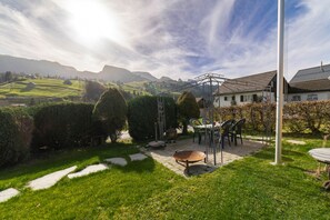 Un jardin agrémenté d’une pergola, d’un espace salon extérieur et offrant une vue sur la campagne.